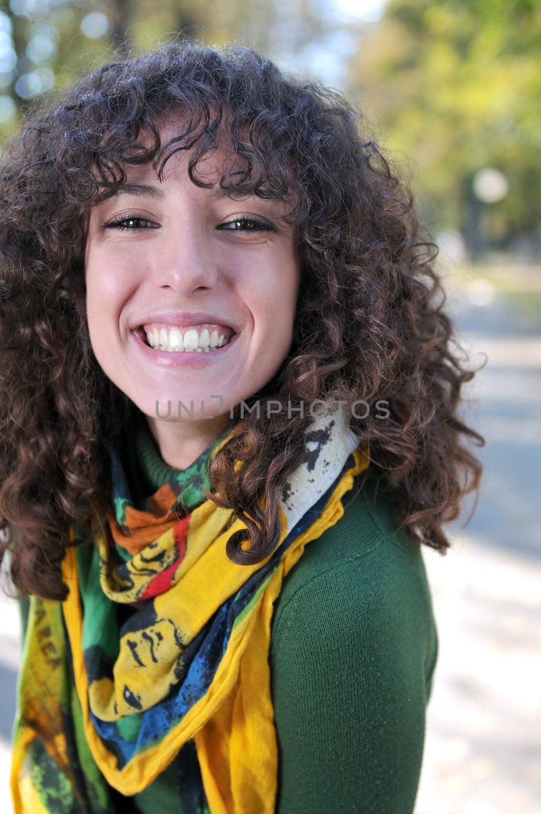 Young curly woman smiling outdoors in nature