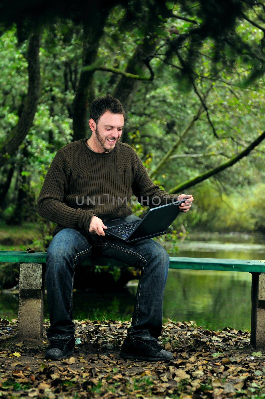 one young businessman working on laptop outdoor with green nature in background