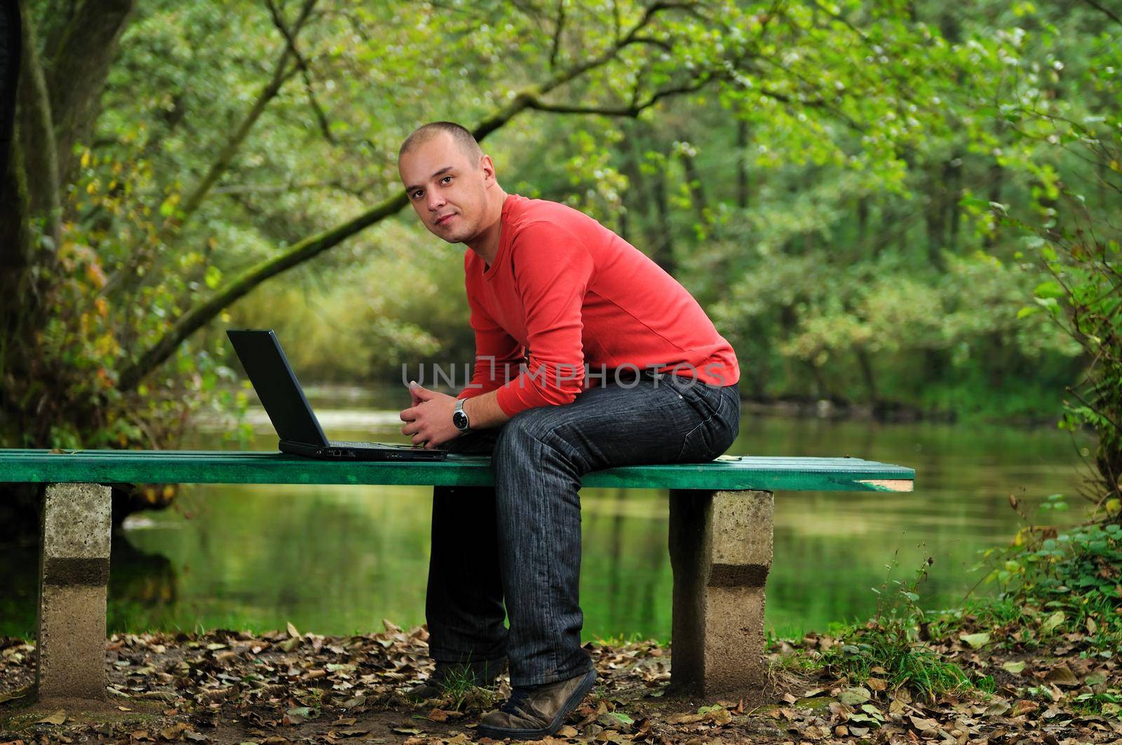 one young businessman working on laptop outdoor with green nature in background