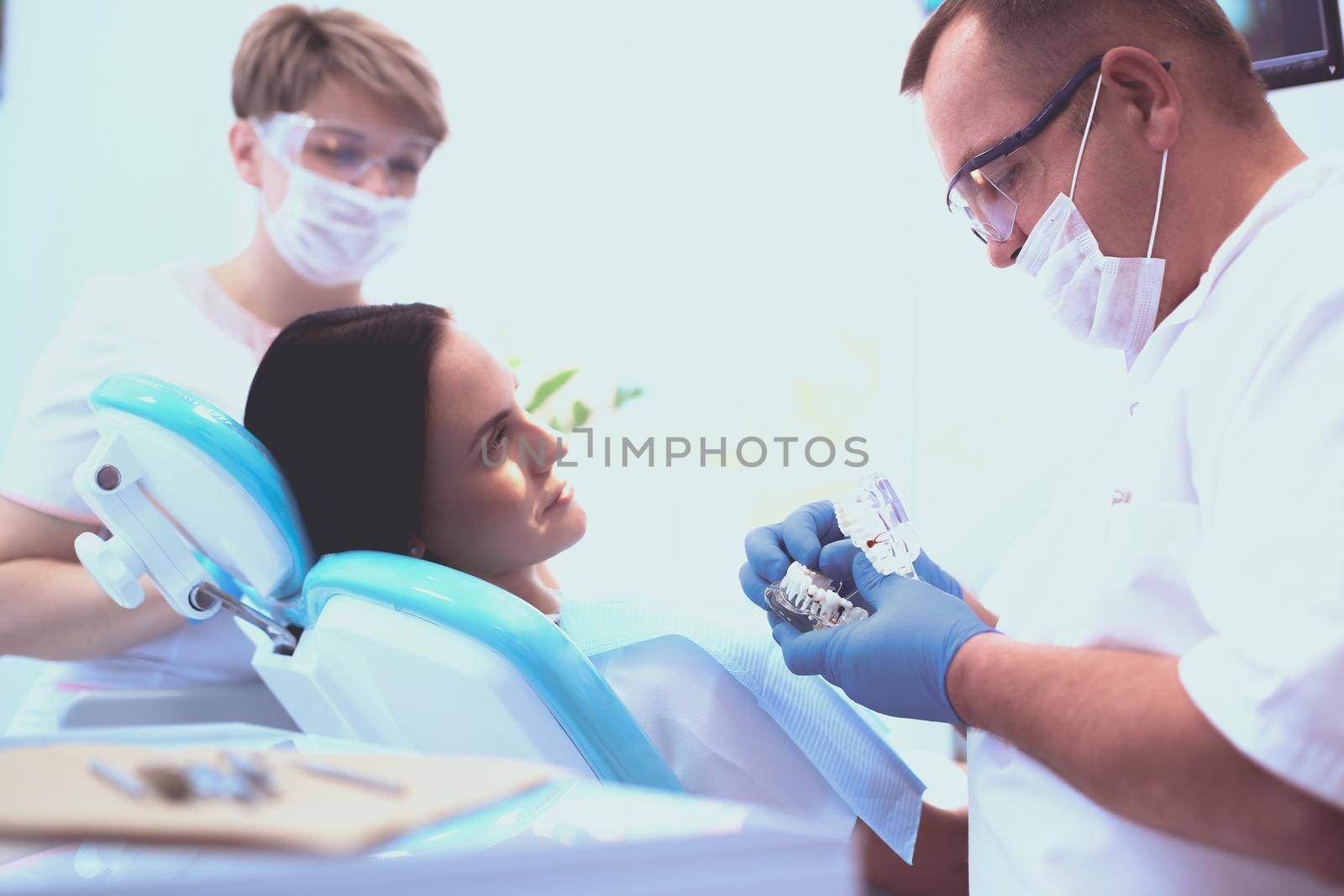Portrait of a dentist who treats teeth of young woman patient by lenets