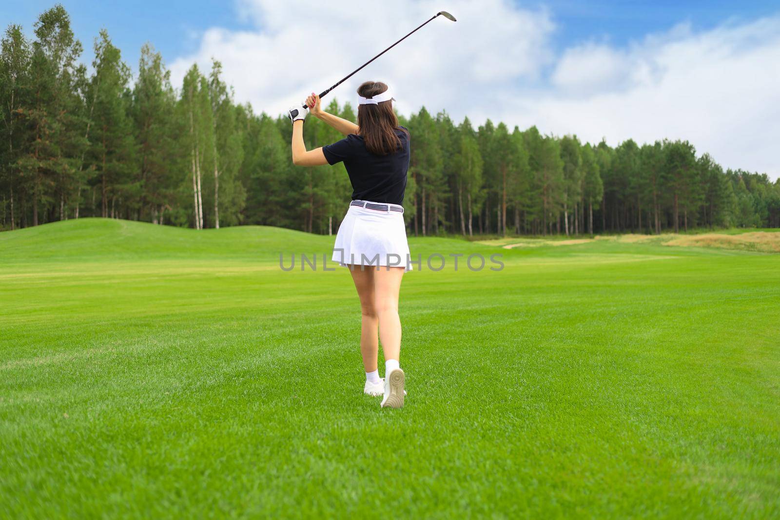 Woman golfer hits an fairway shot towards the club house