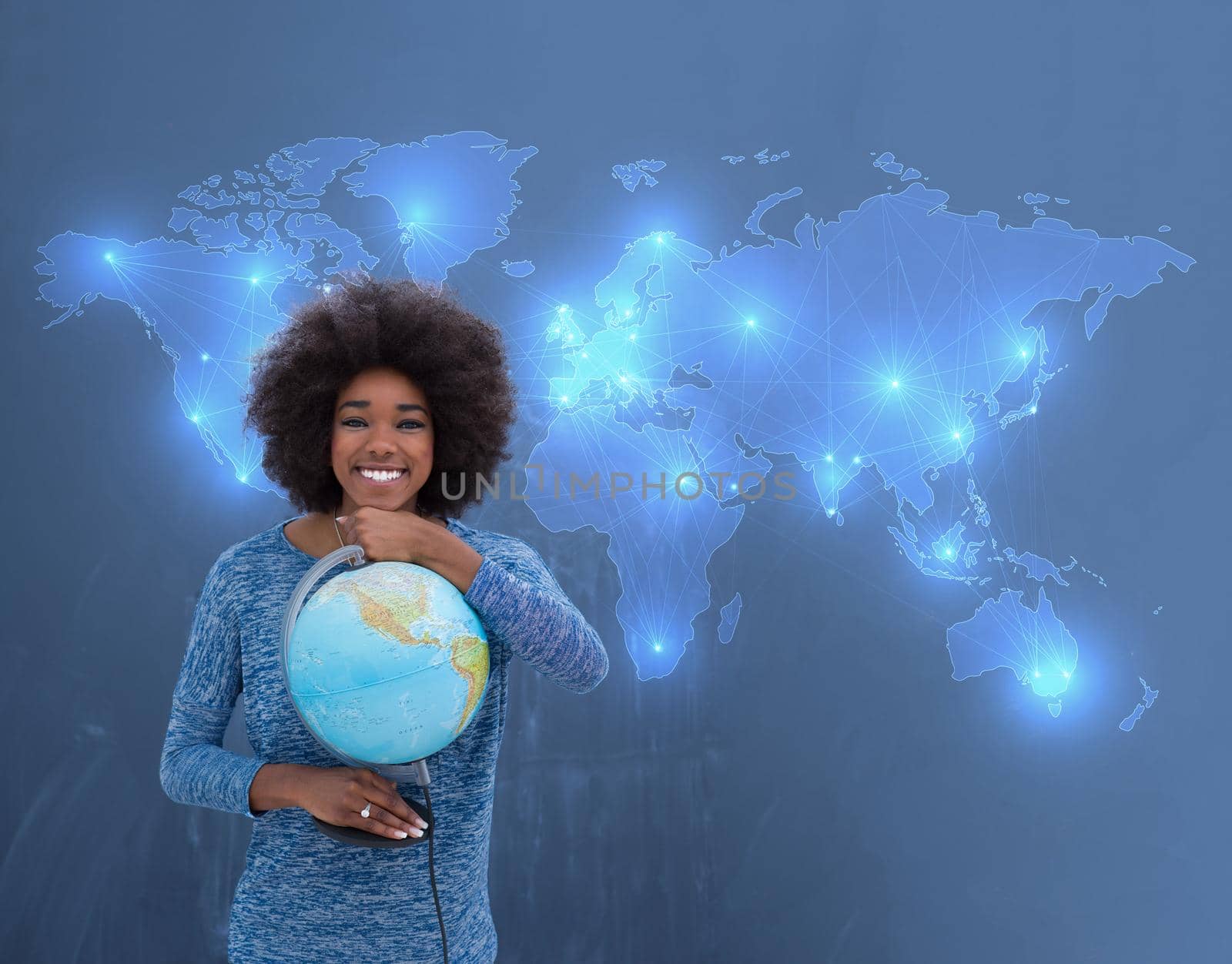 portrait of a beautiful friendly African American woman with a curly afro hairstyle and lovely smile holding Globe of the world isolated on a gray background