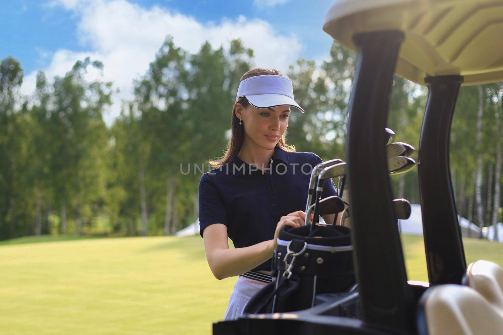 Professional woman golf player choosing the golf club from the bag