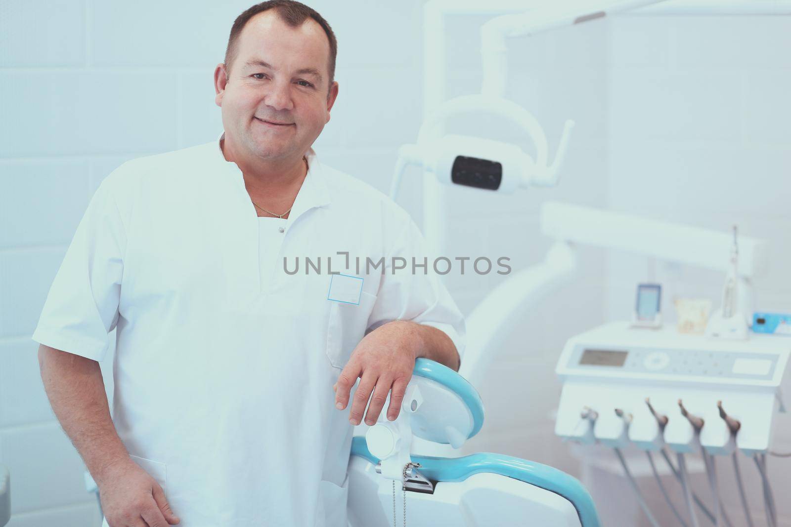 Portrait of a smiling dentist standing in dental clinic.