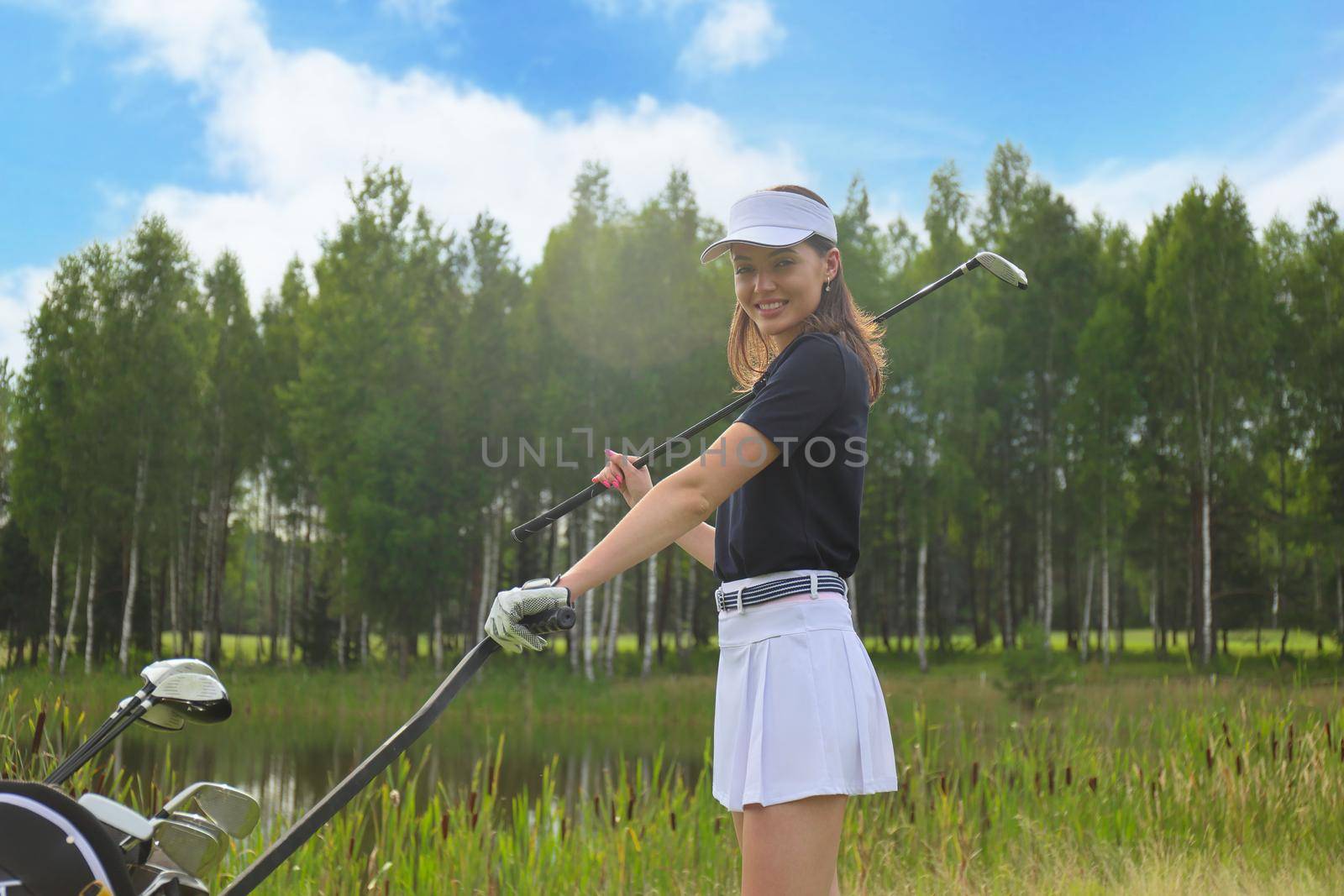 Beautiful golf woman player carrying a golf bag and smiling