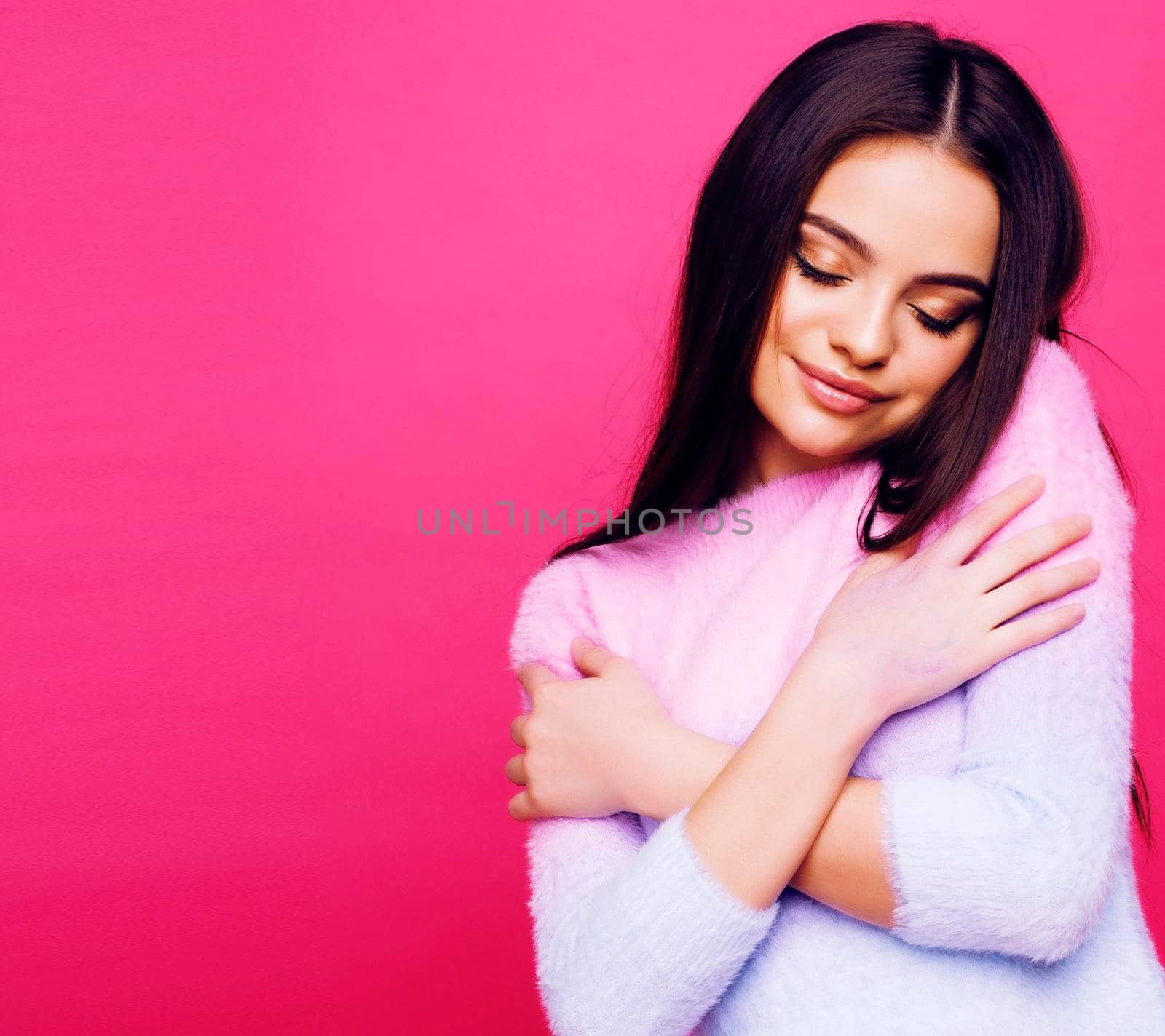 young pretty girl with brunette long hair posing cheerful on pink background, lifestyle people concept close up