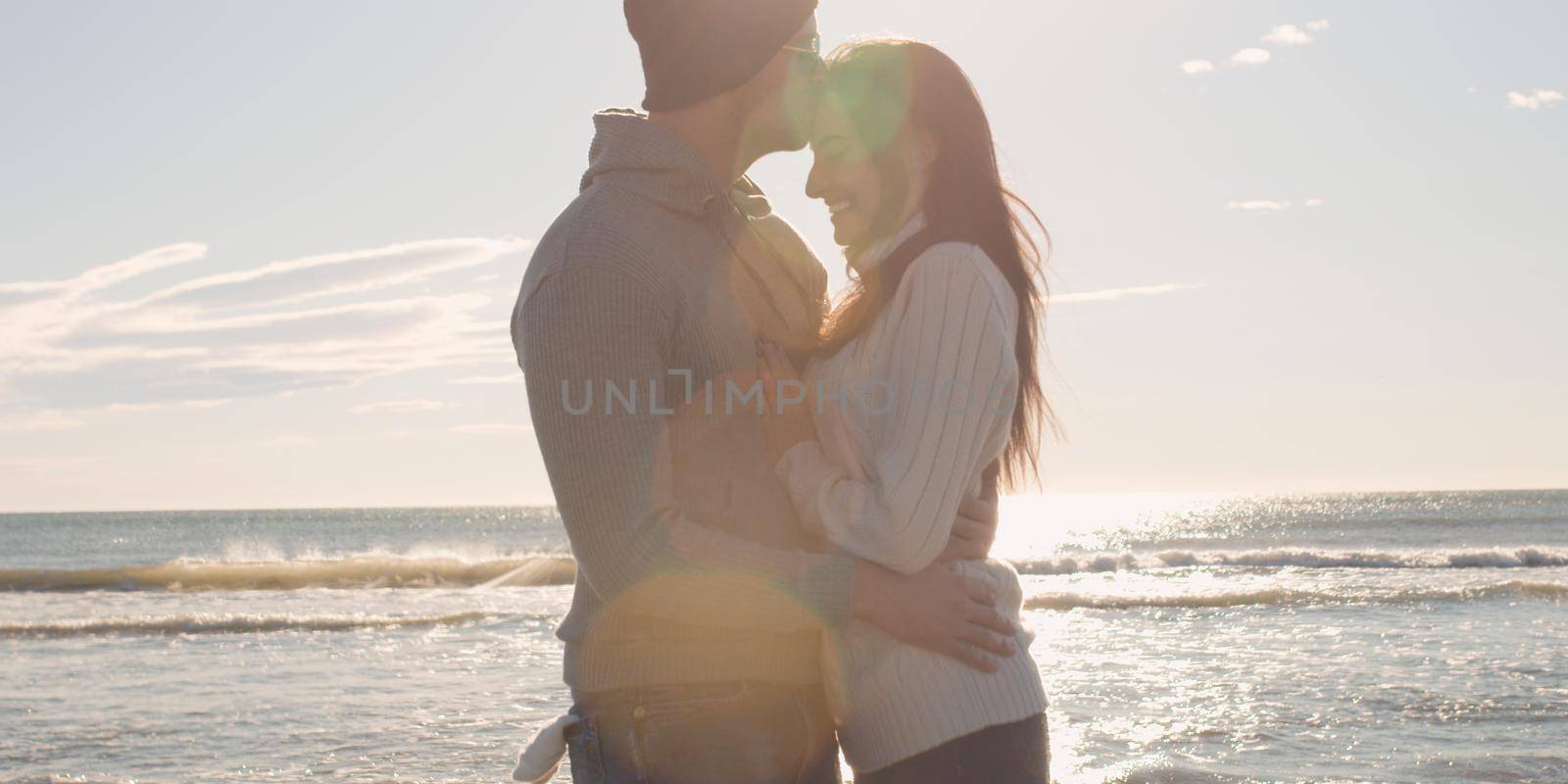 Cool Couple Laughing and hugging In Front Of Beach at beautiful autumn day