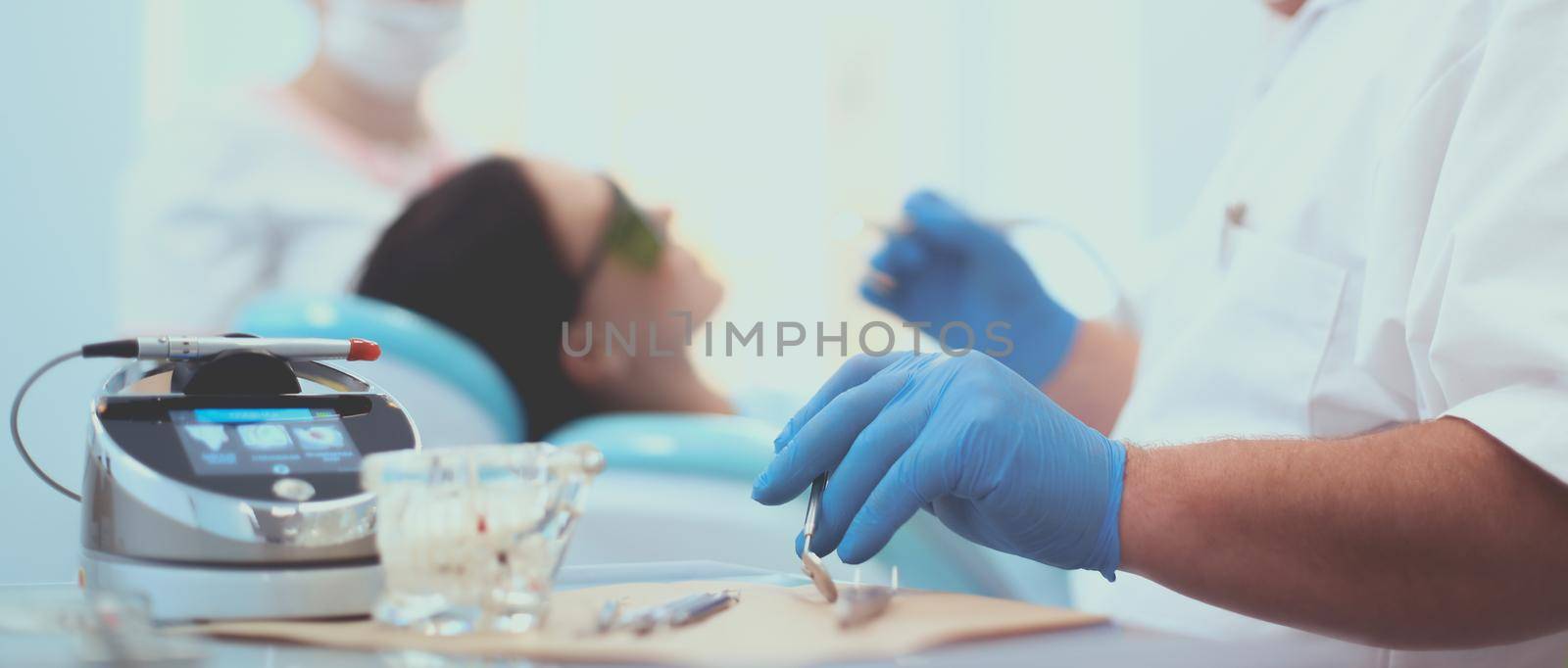 Man dentist working at his patients teeth by lenets