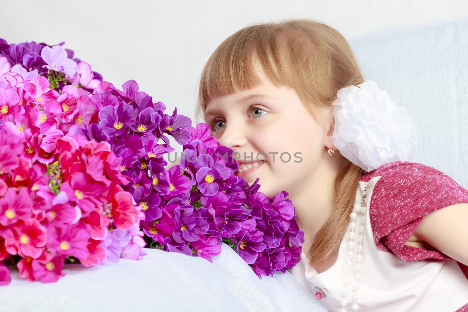 Girl sits next to a bouquet of flowers. by kolesnikov_studio