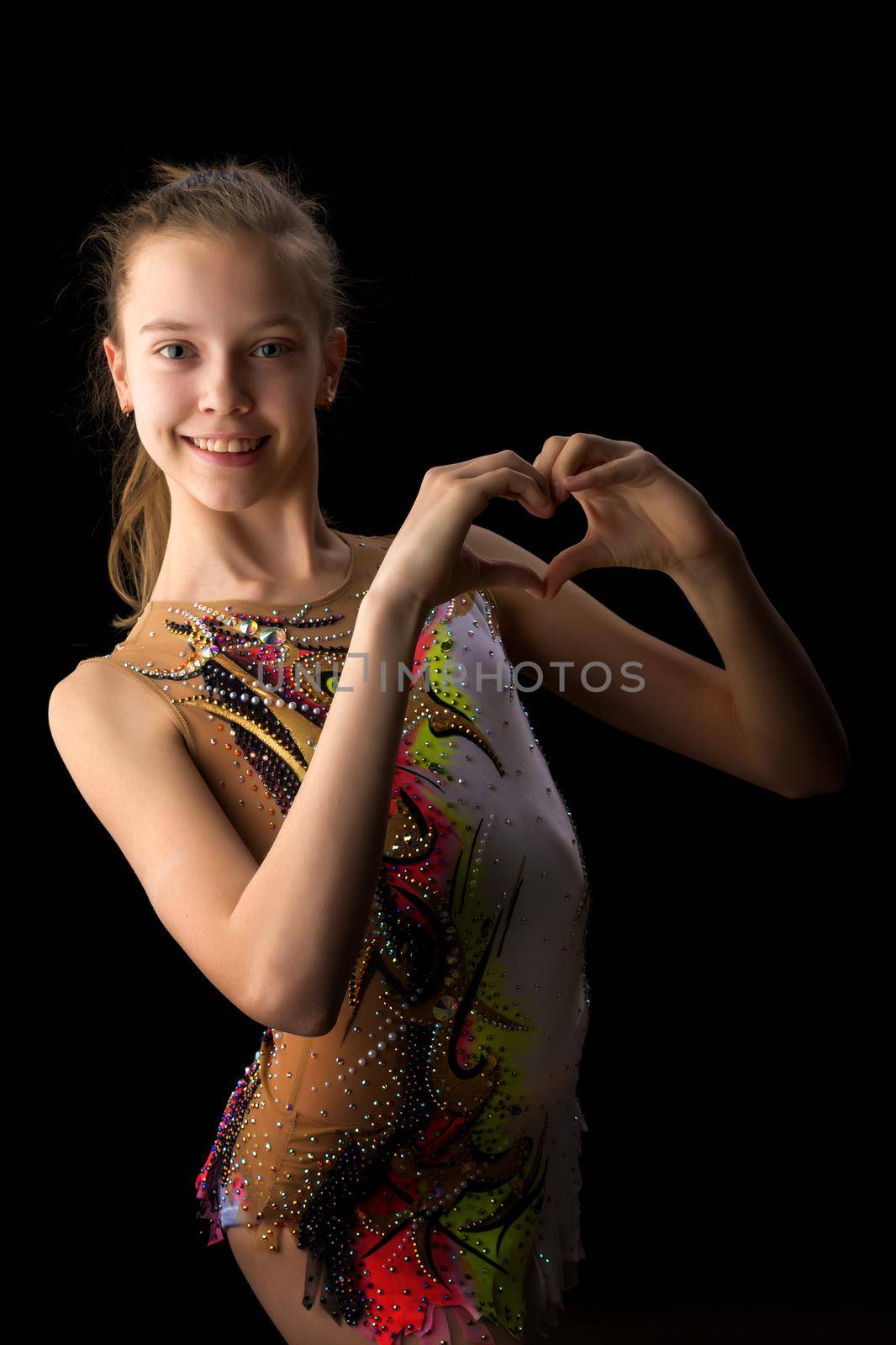A teenage girl in a gymnastic swimsuit on a black background. The concept of sport, beauty, people, healthy lifestyle.