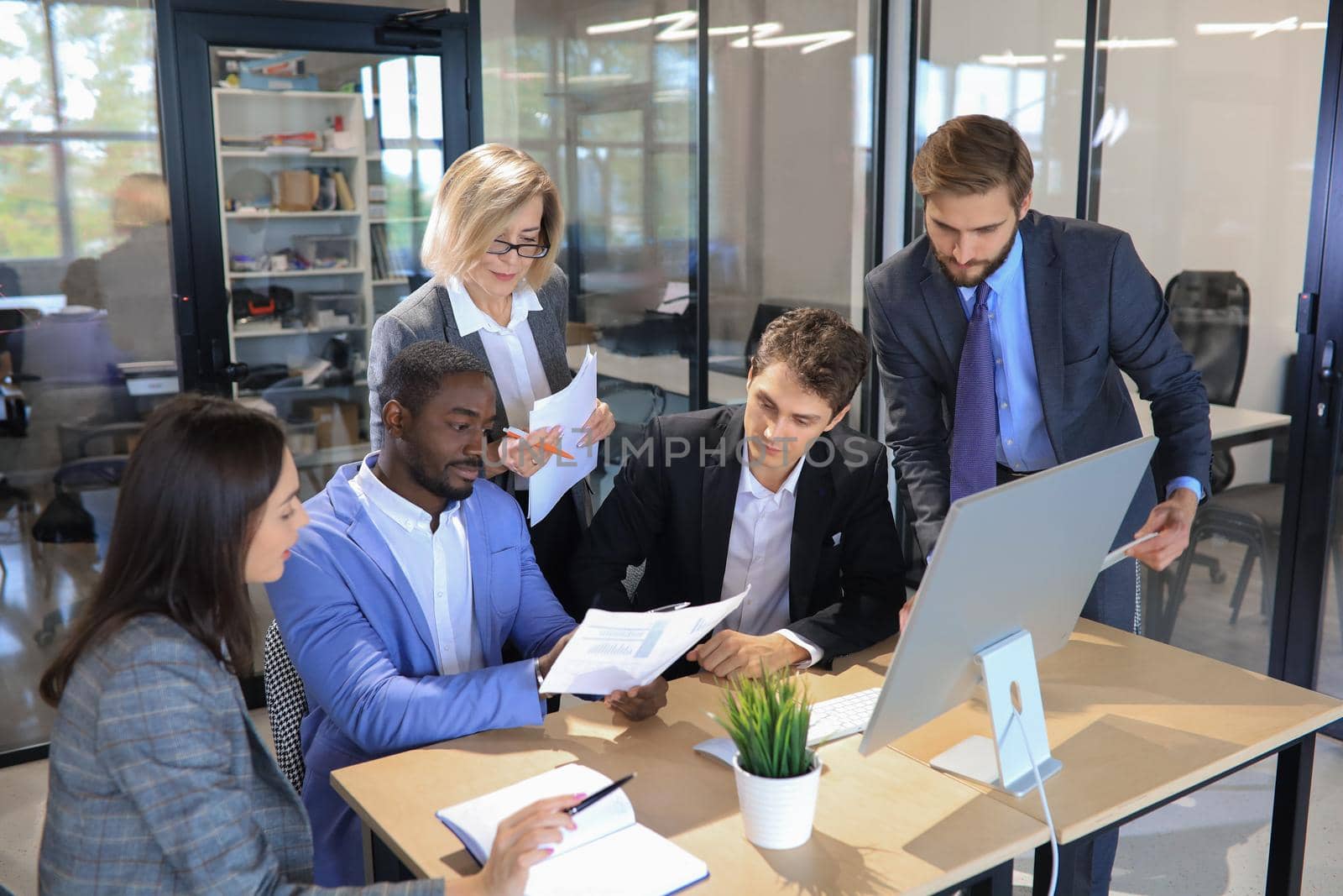 Five business people during a meeting sitting around a table