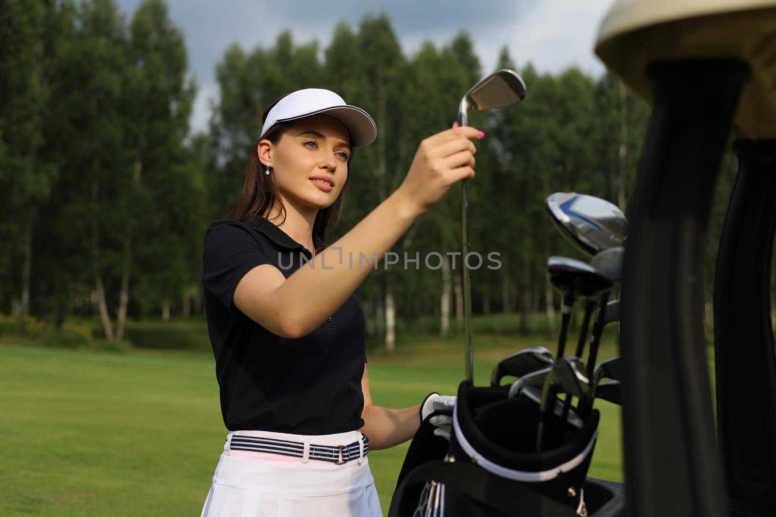 Professional woman golf player choosing the golf club from the bag
