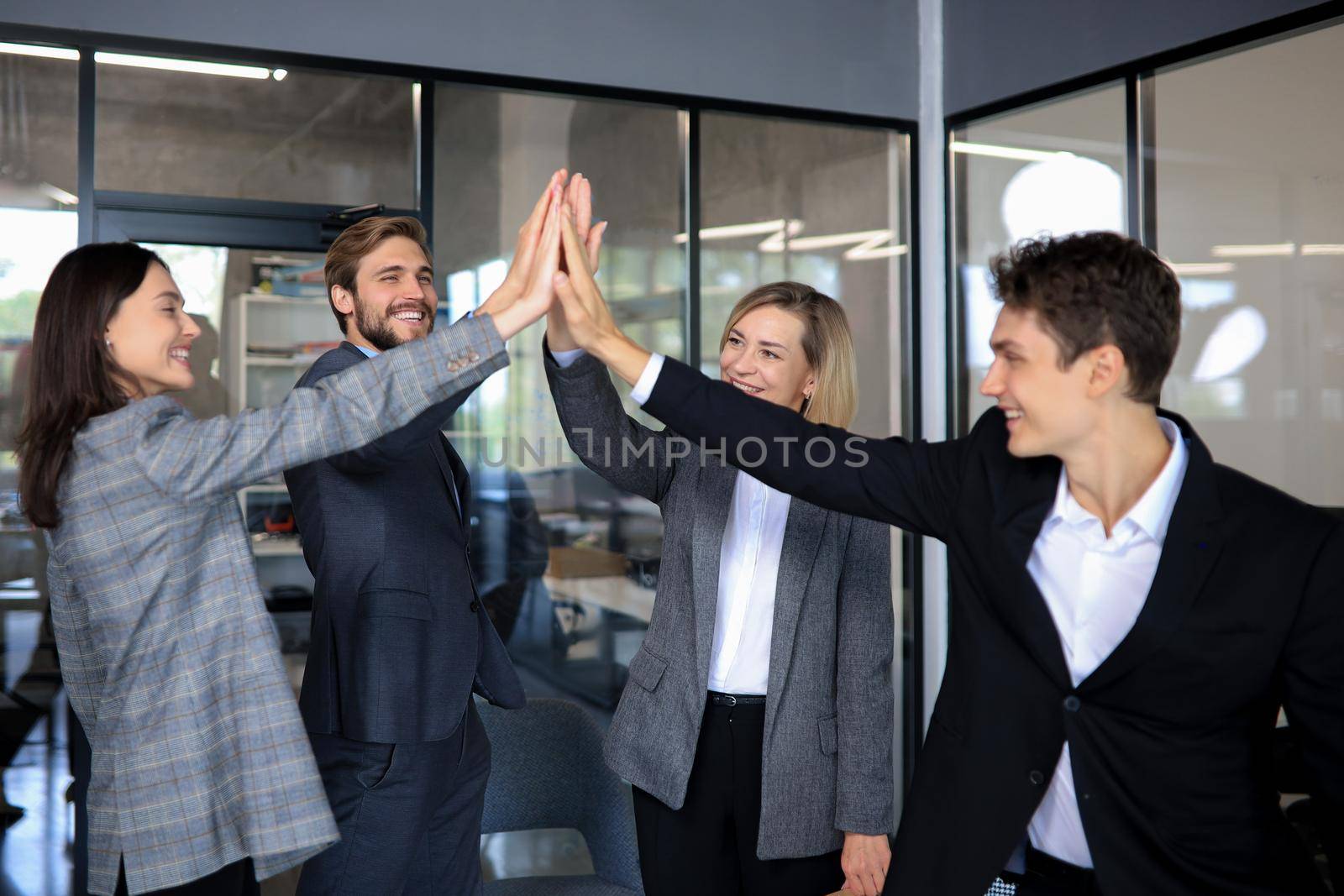 Happy people standing in office and giving high five to their colleagues. by tsyhun