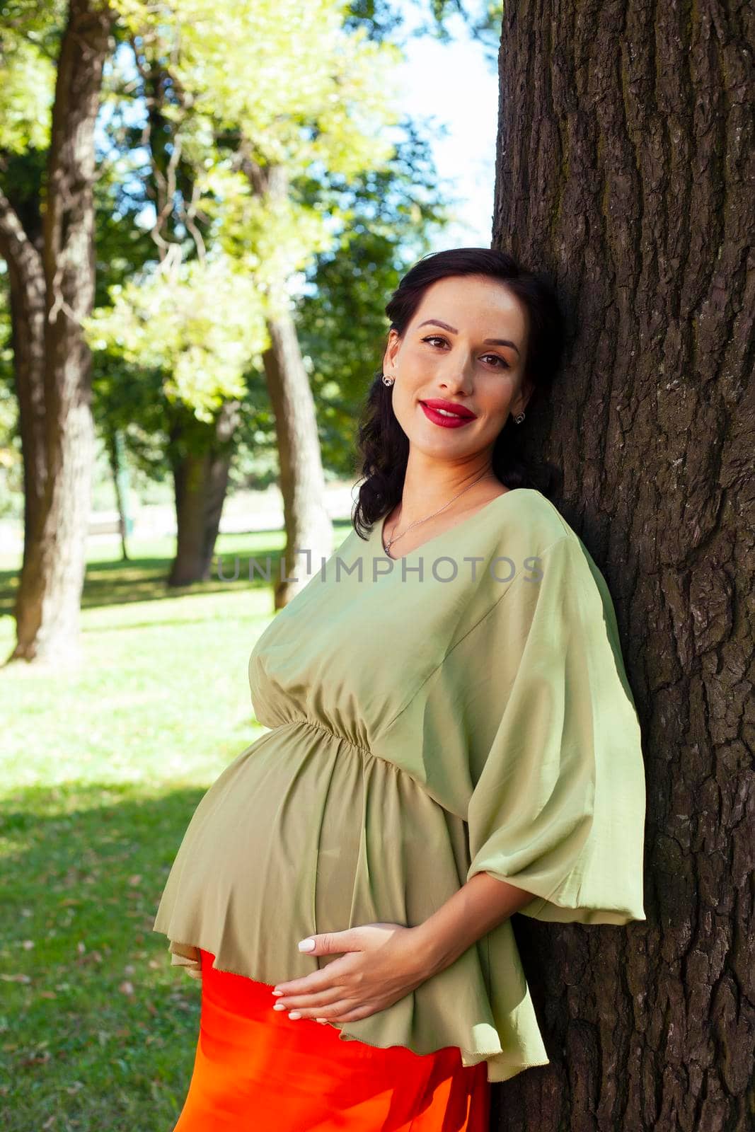 young pretty brunette pregnant woman outdoor in green park happy smiling, lifestyle people concept close up