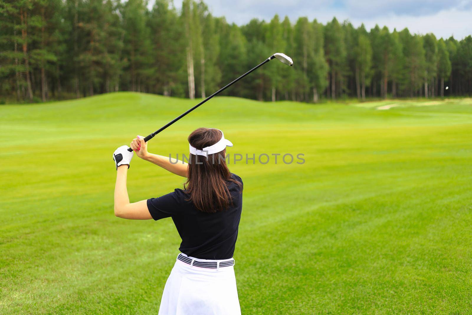 Woman golfer hits an fairway shot towards the club house