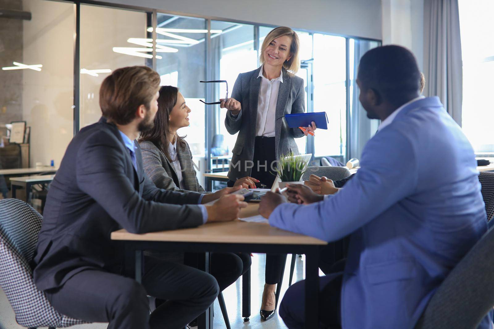 Female boss addressing meeting around boardroom table. by tsyhun