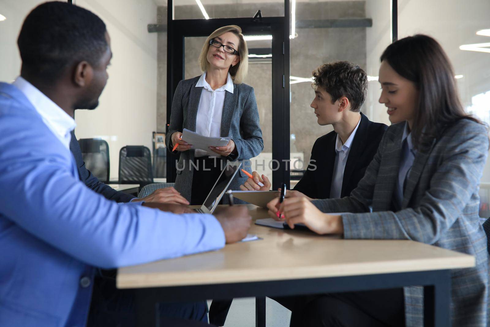 Female boss addressing meeting around boardroom table