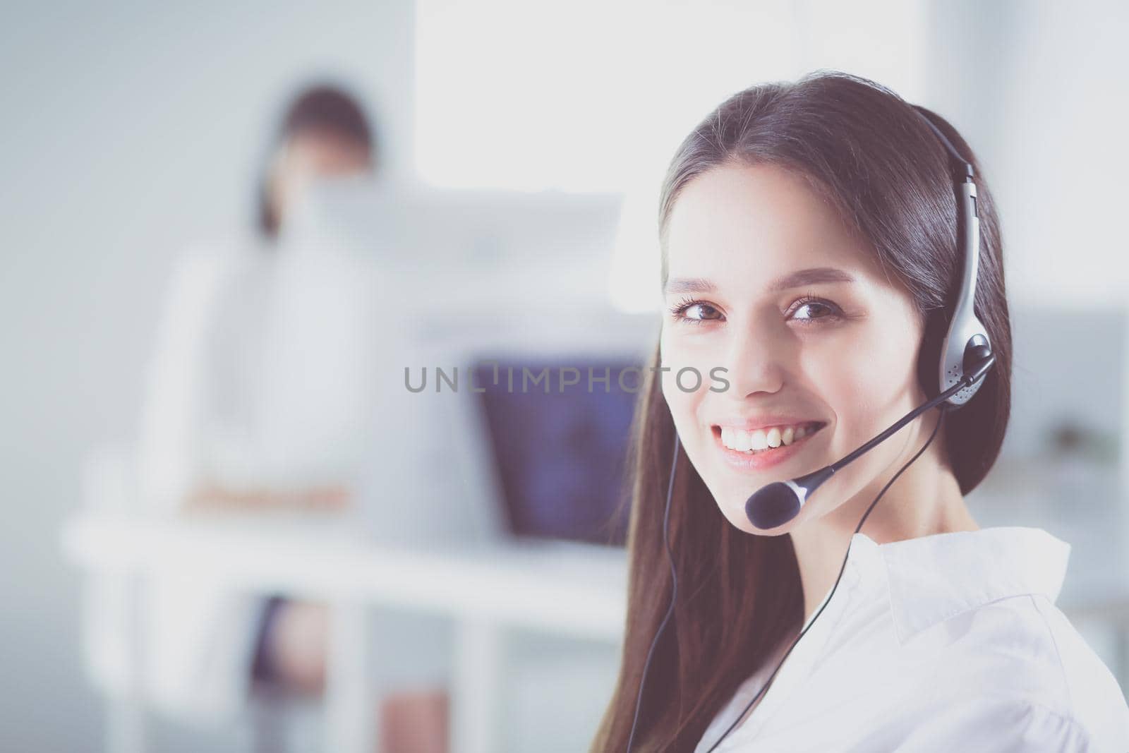 Smiling businesswoman or helpline operator with headset and computer at office.