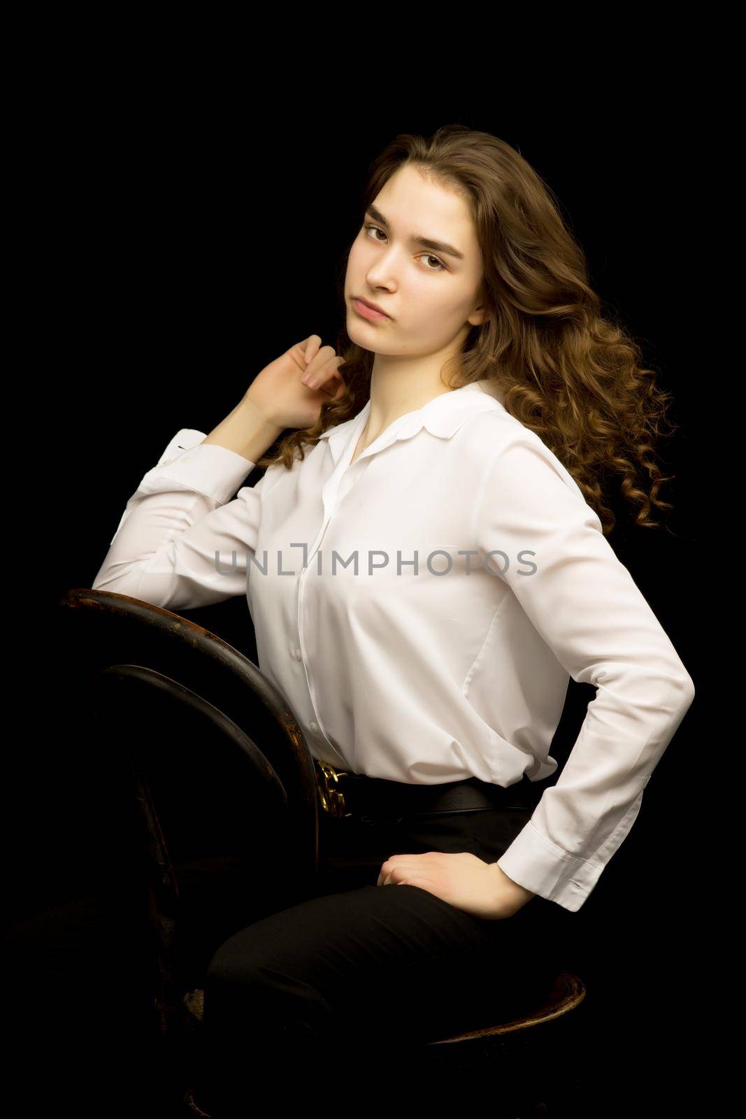 Beautiful, fashionable girl teenager studio photo on a black background. The concept of style and fashion layout for the magazine.