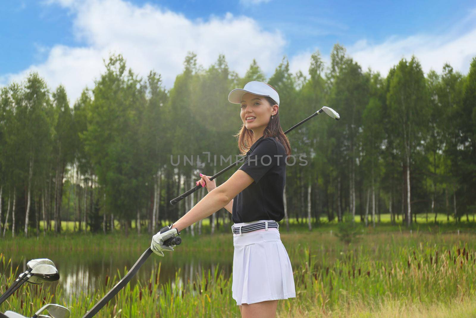 Beautiful golf woman player carrying a golf bag and smiling