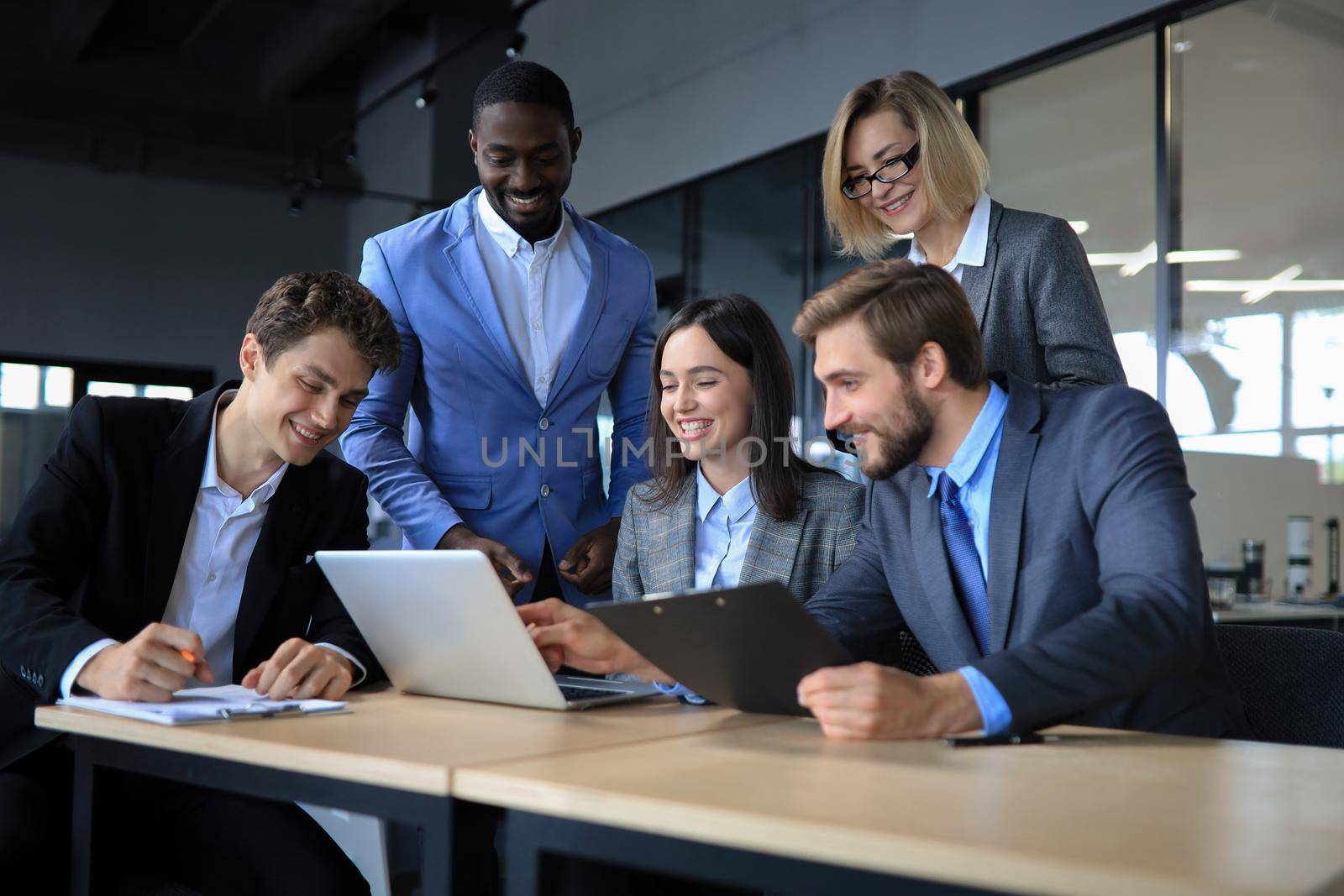 Happy business people laugh near laptop in the office. Successful team coworkers joke and have fun together at work