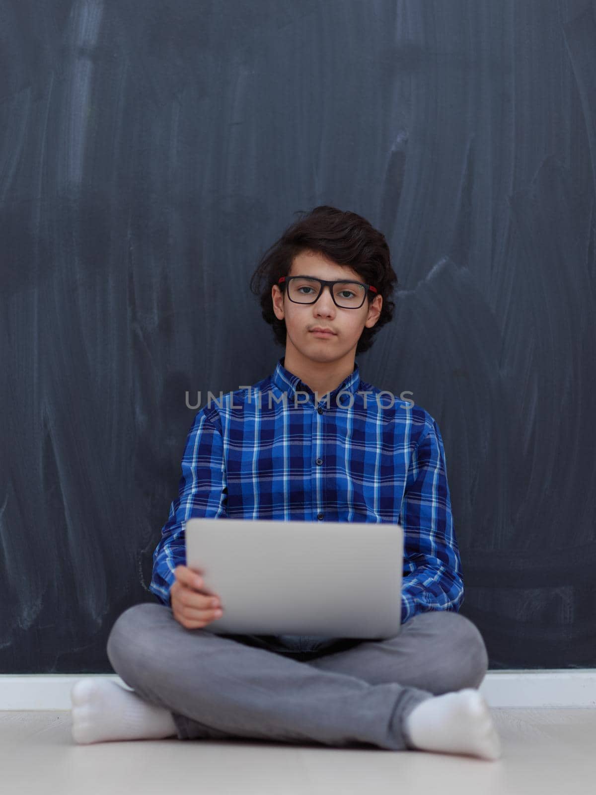 Arab teenager using laptop to work on homework and watch online education while staying at home cause coronavirus pandemic quarantine