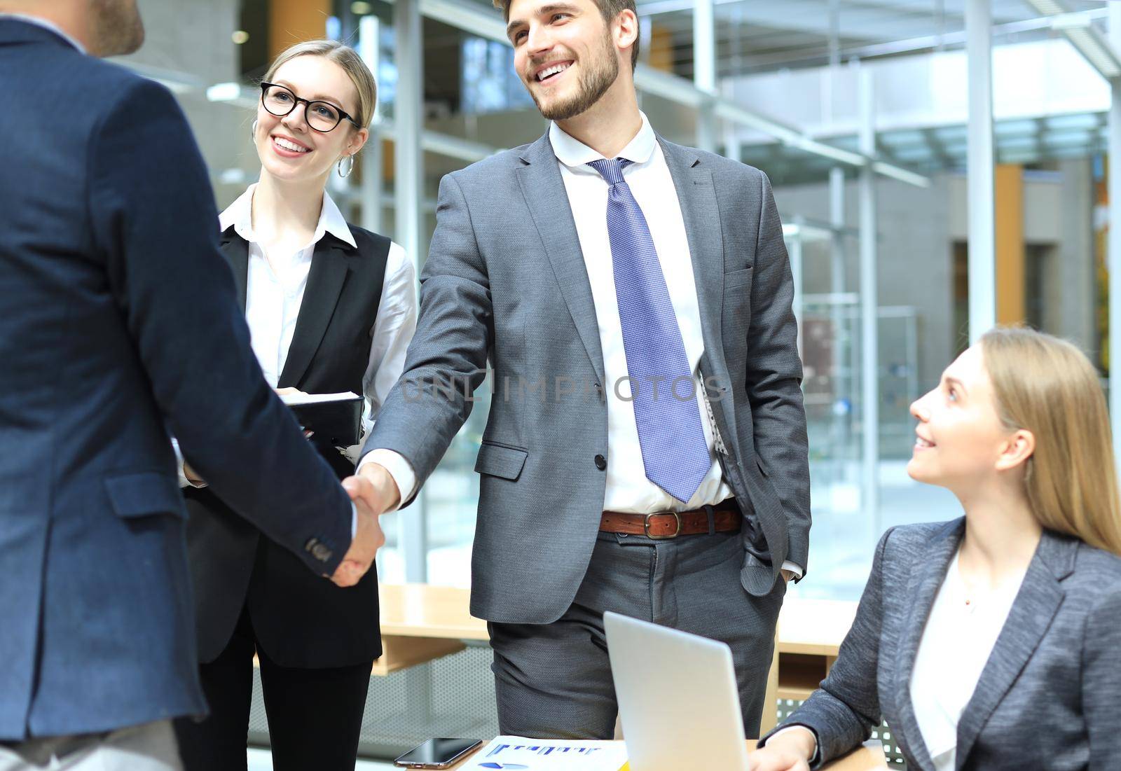 Welcome to our team. Young modern businessmen shaking hands while working in the creative office