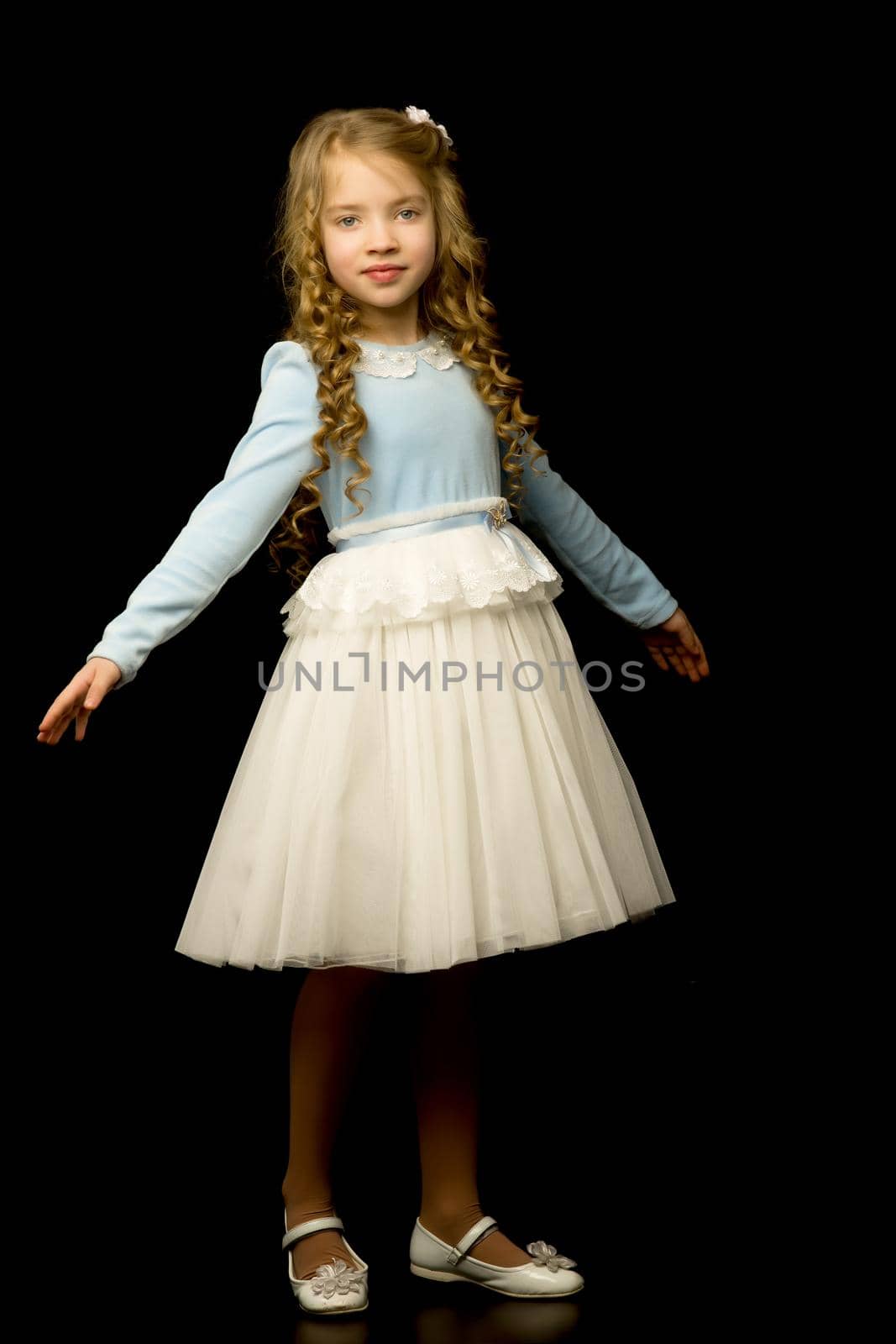 Beautiful little girl, studio portrait on a black background. The concept of a happy childhood, style and fashion.