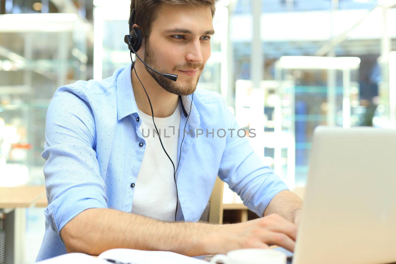 Happy young male customer support executive working in office. by tsyhun