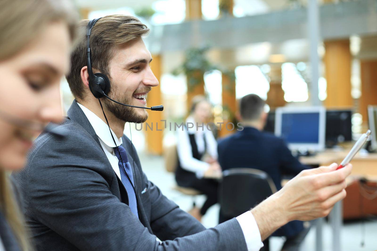 Portrait of call center worker accompanied by his team. Smiling customer support operator at work