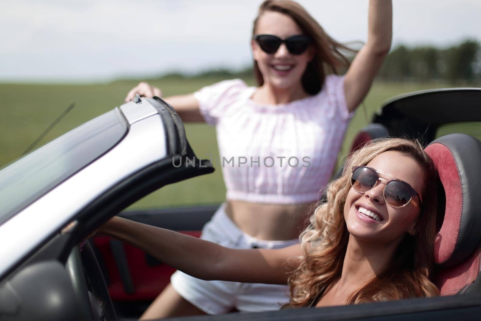 close up.two happy young women in a convertible car by asdf