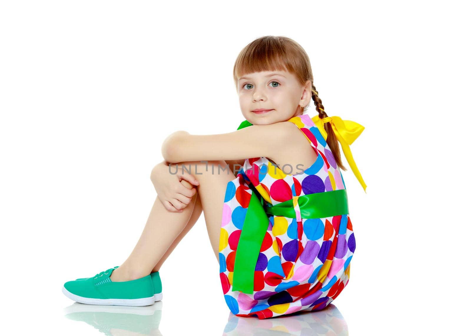 A little girl in a dress with a pattern from multi-colored circl by kolesnikov_studio