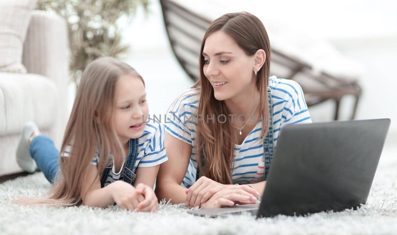 mom and her little daughter using a laptop in their free time by asdf