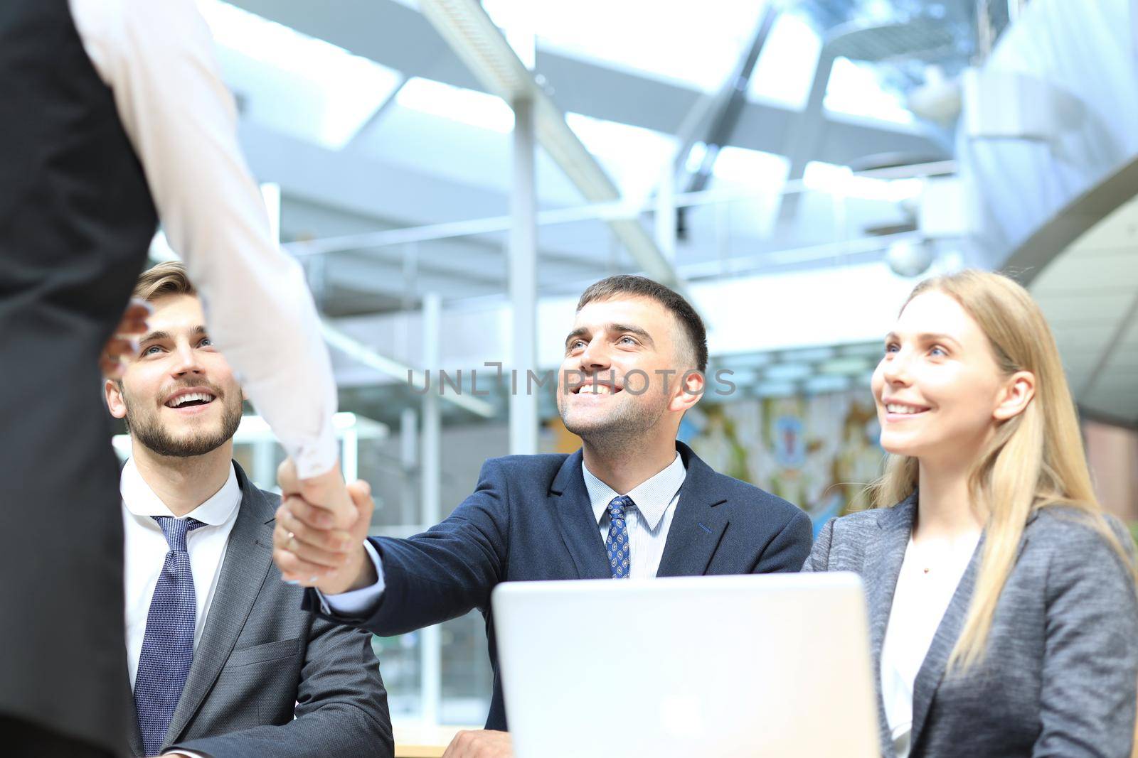 Welcome to our team. Young modern businessmen shaking hands while working in the creative office