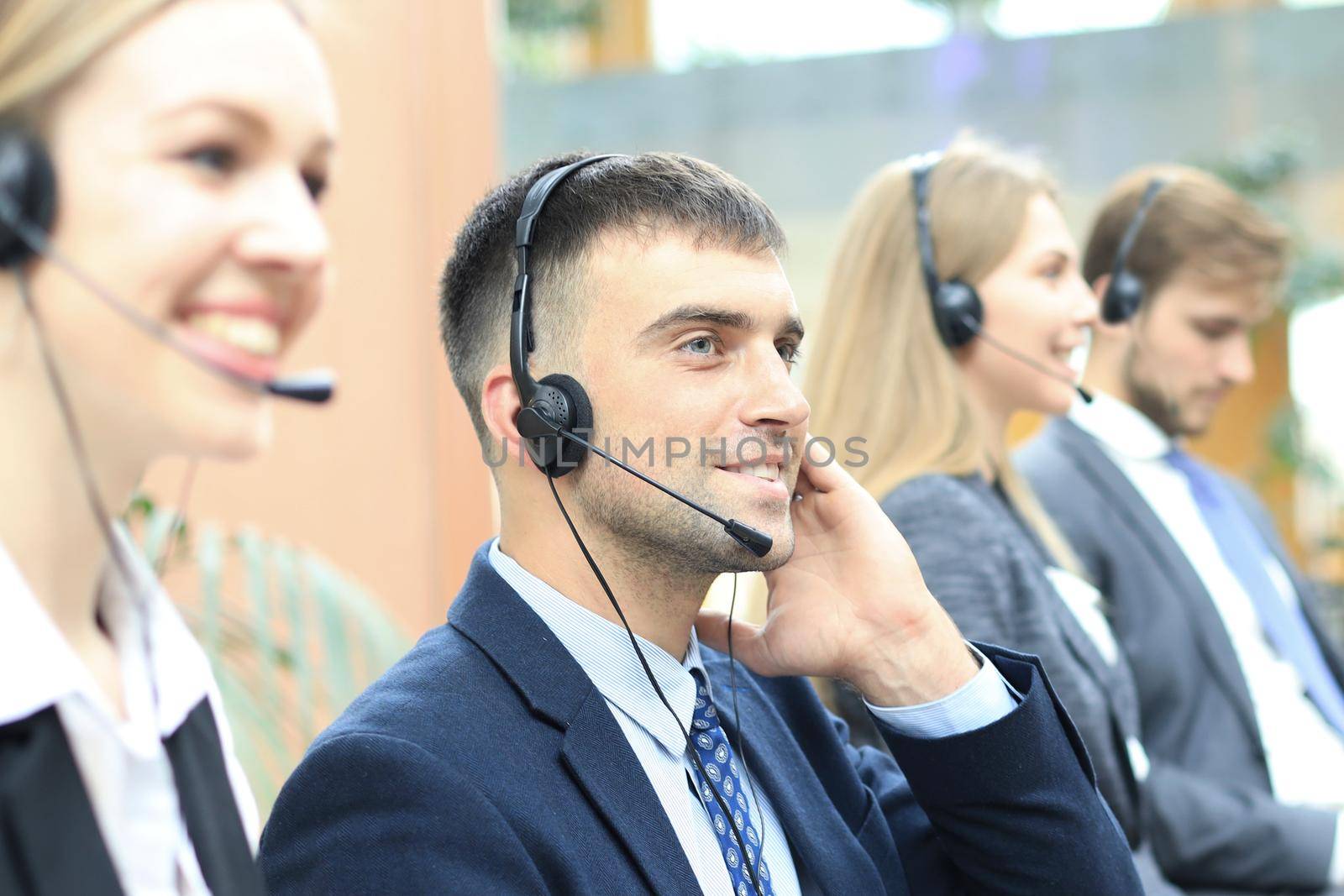 Portrait of call center worker accompanied by his team. Smiling customer support operator at work