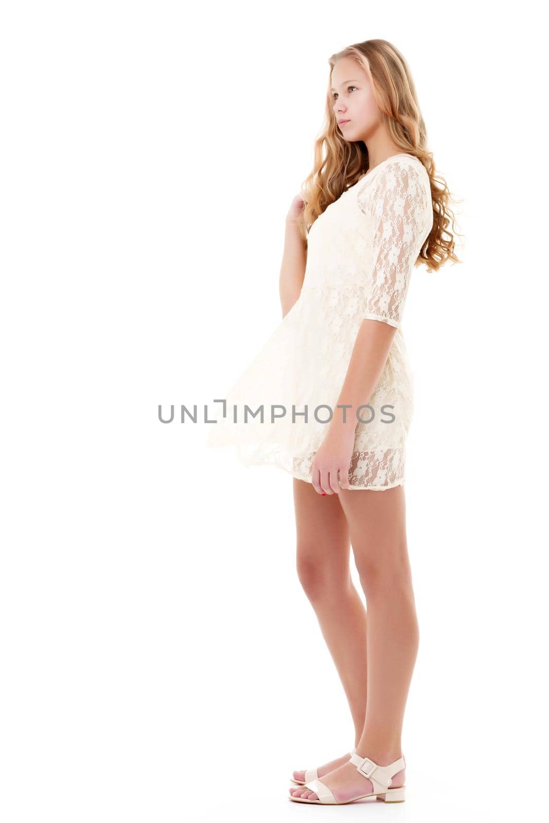 Portrait of a positive and stylish little girl in a summer dress, rejoices in the wind that blows and moves her dress and hair. The concept of beauty and fashion. Isolated on white background.