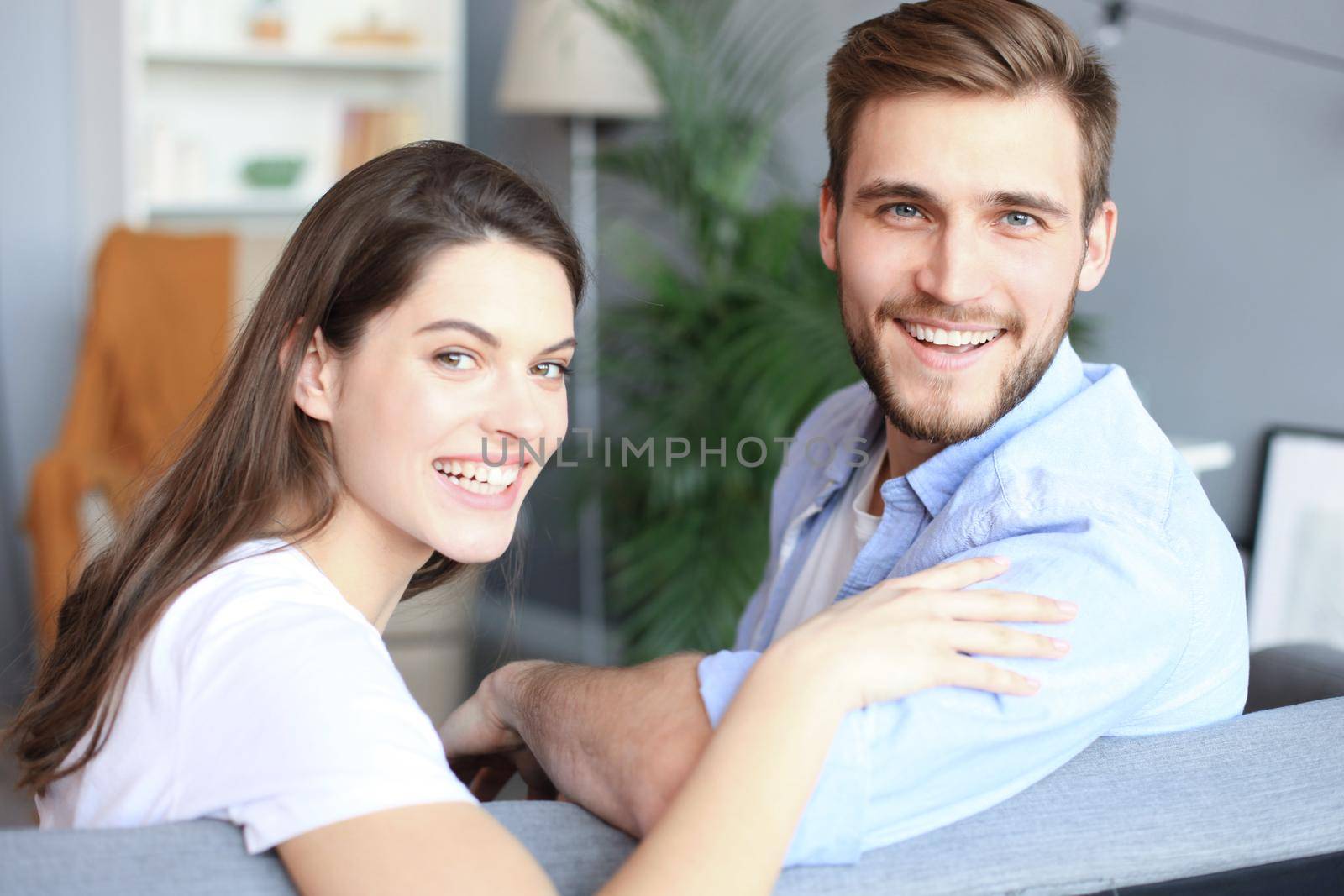 Portrait of cute young couple sitting in sofa. by tsyhun