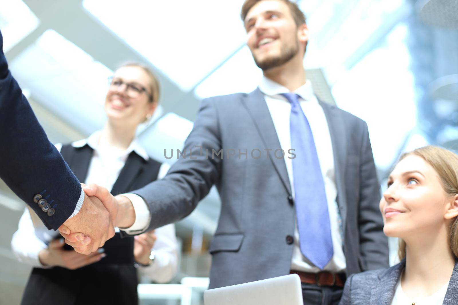 Welcome to our team. Young modern businessmen shaking hands while working in the creative office