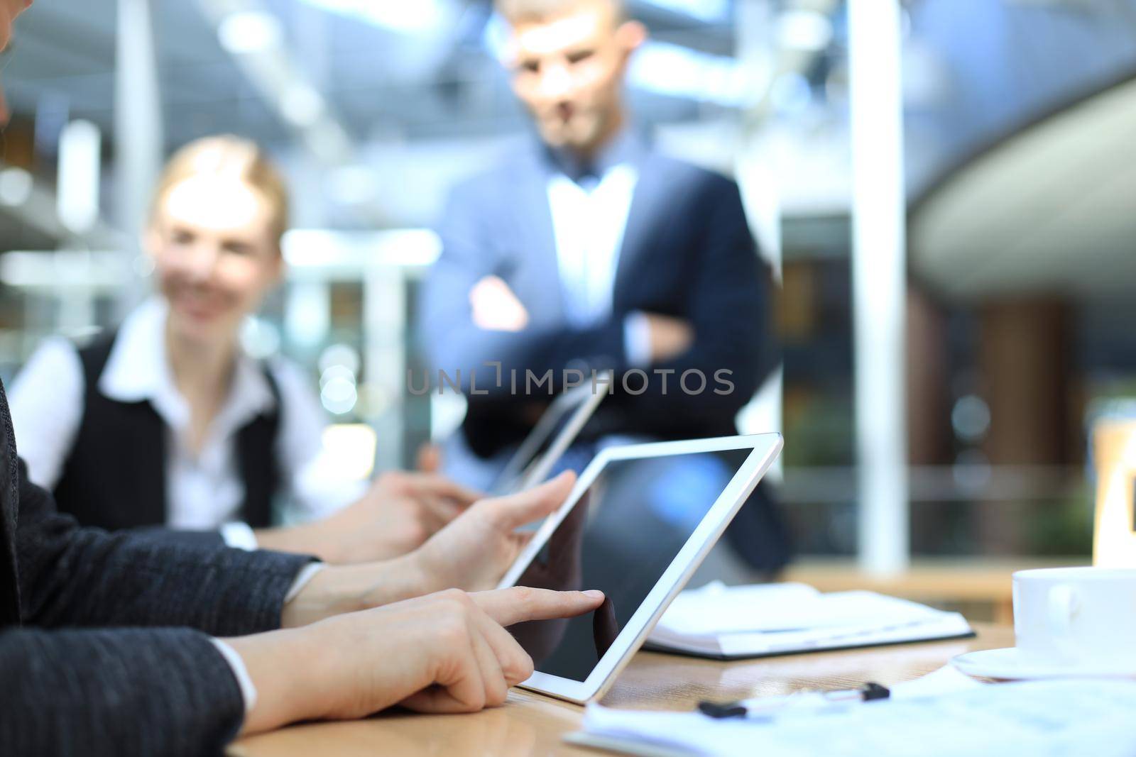 Image of human hand pointing at touchscreen in working environment at meeting