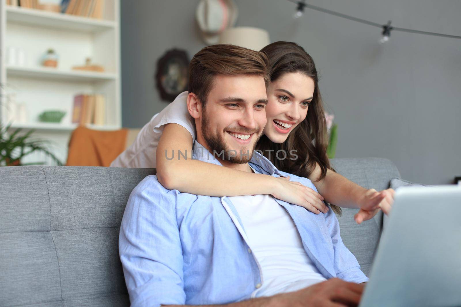 Young couple doing some online shopping at home, using a laptop on the sofa. by tsyhun