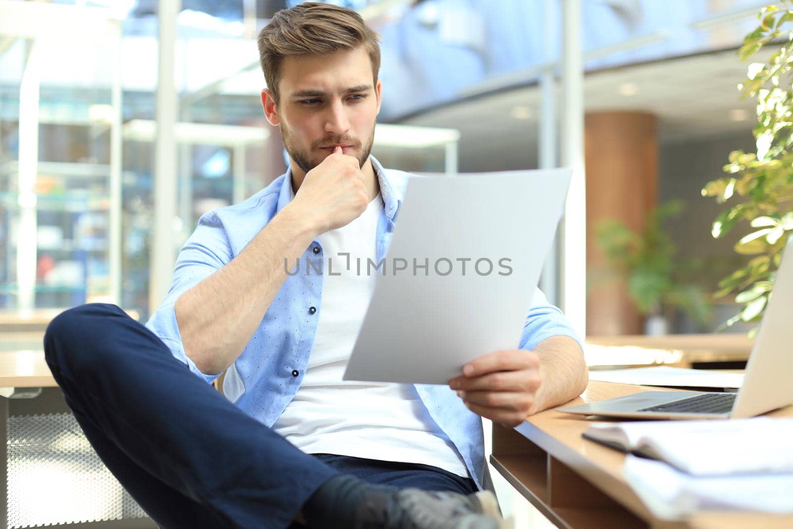 Portrait of young man sitting at his desk in the office