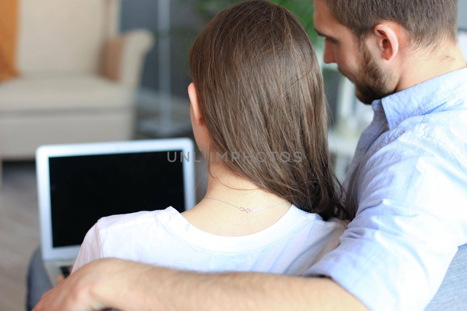 Young couple doing some online shopping at home, using a laptop on the sofa. by tsyhun