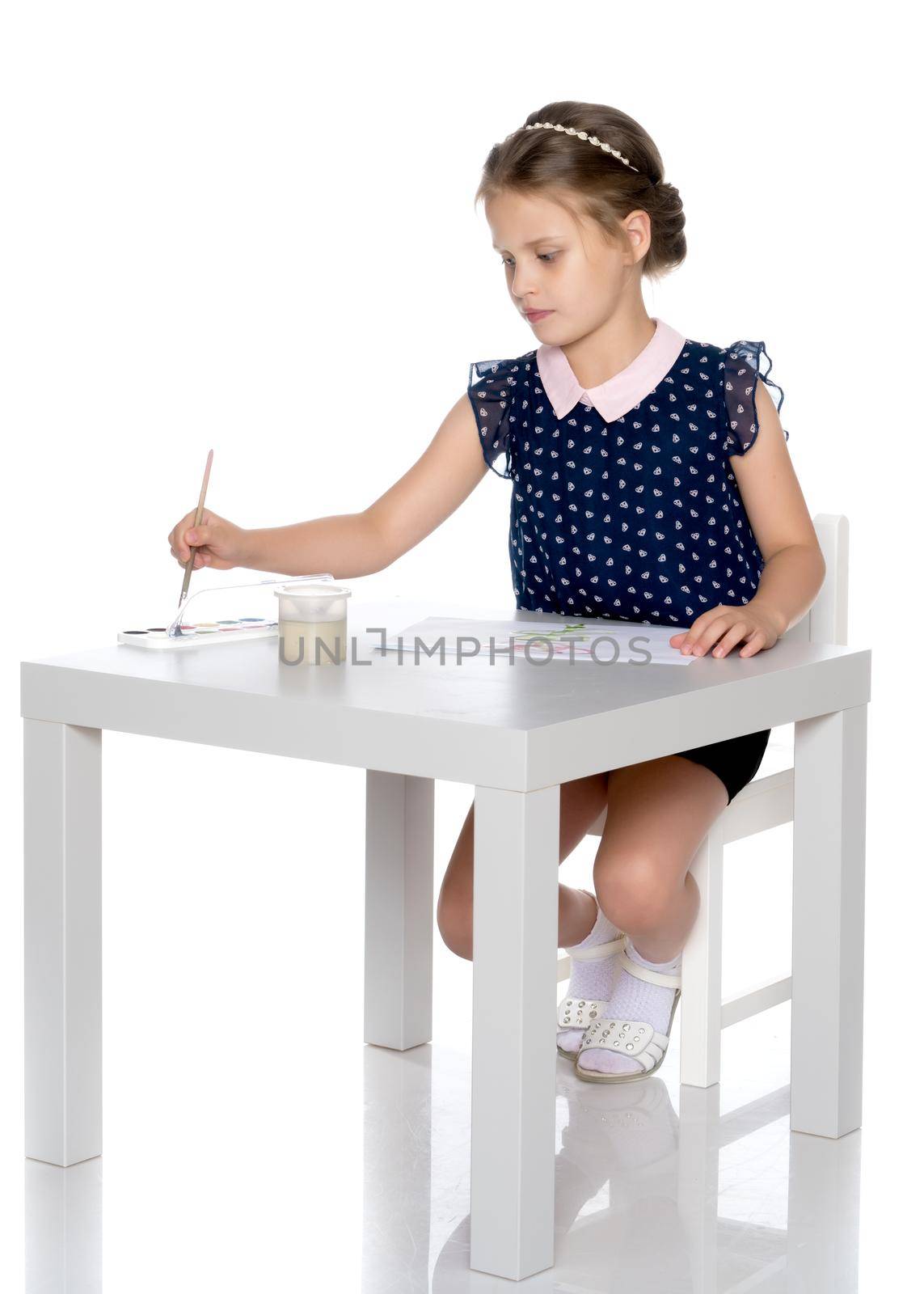 A little girl paints with paint and brush. The concept of children's creativity, happy childhood. Isolated on white background.