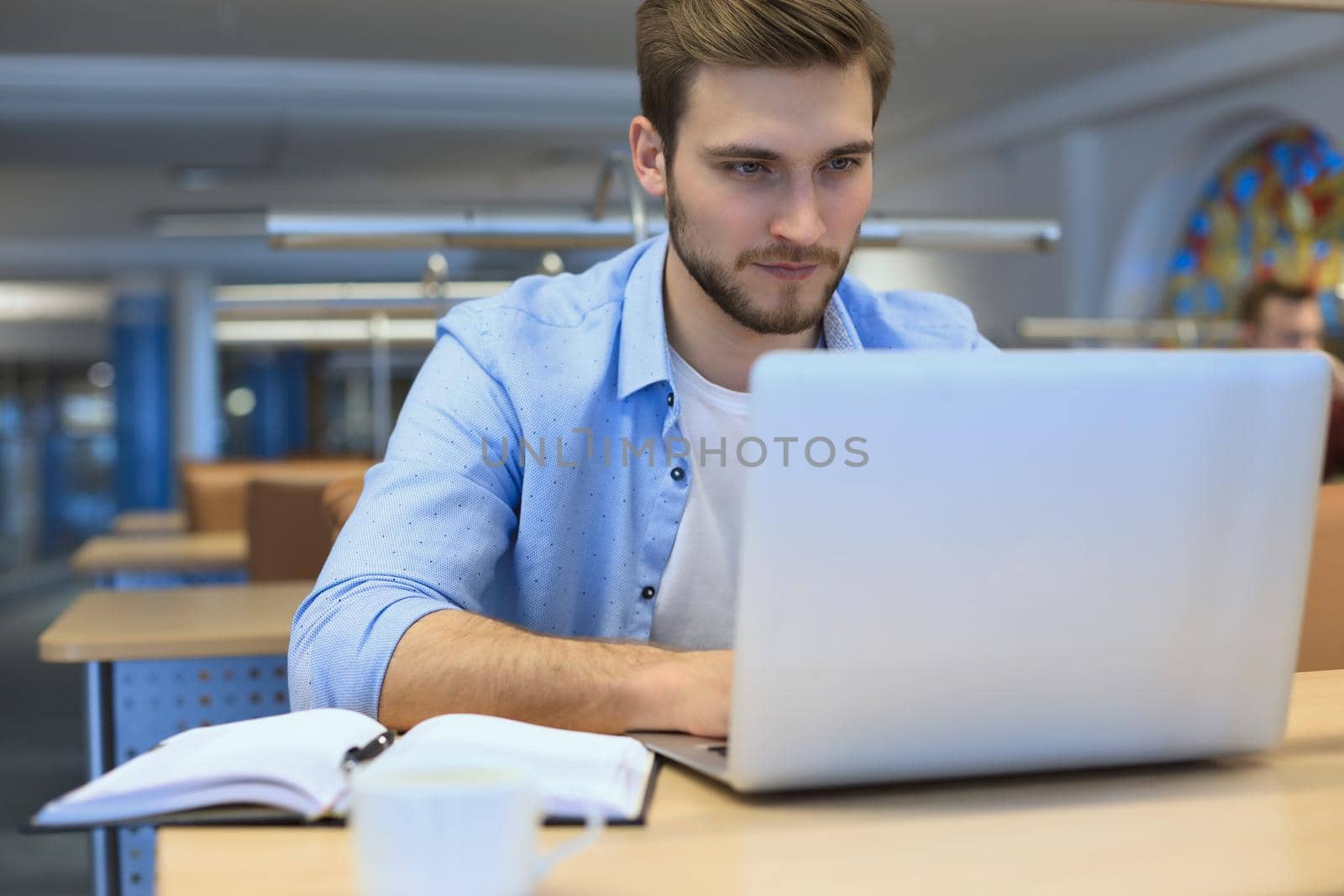 Portrait of young man sitting at his desk in the office