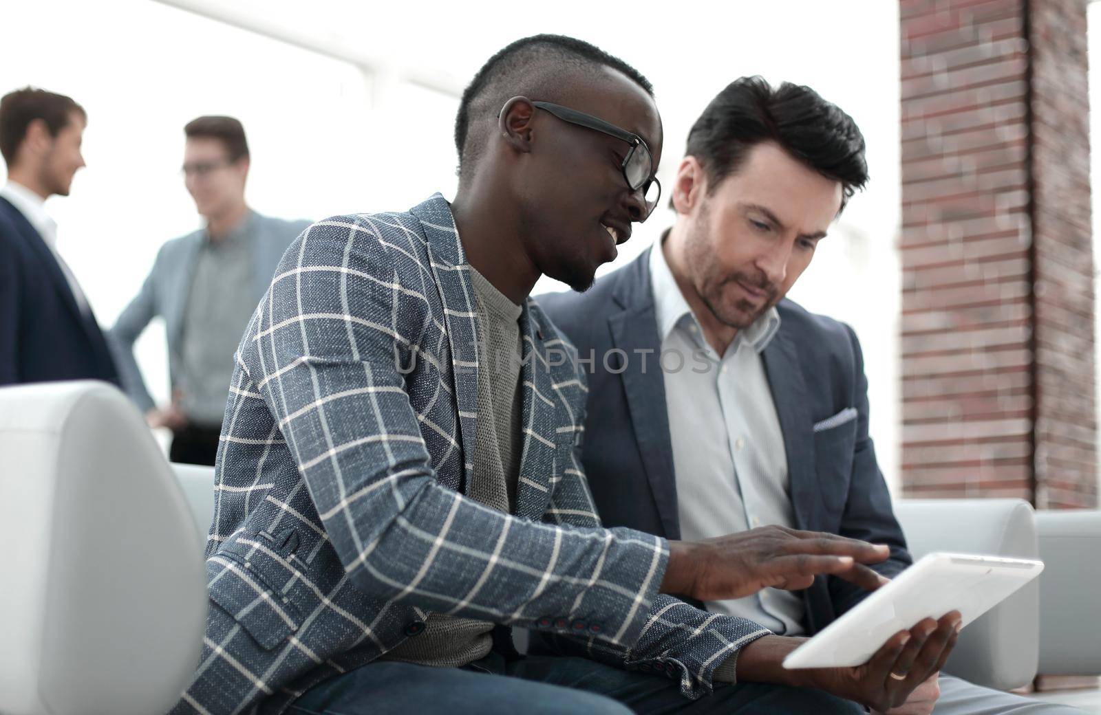two businessmen use a digital tablet by asdf