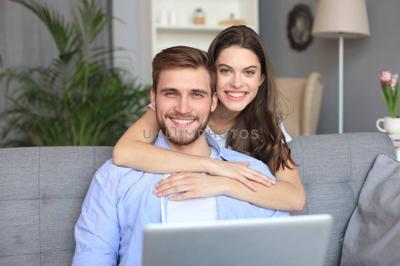 Portrait of cute young couple sitting in sofa. by tsyhun