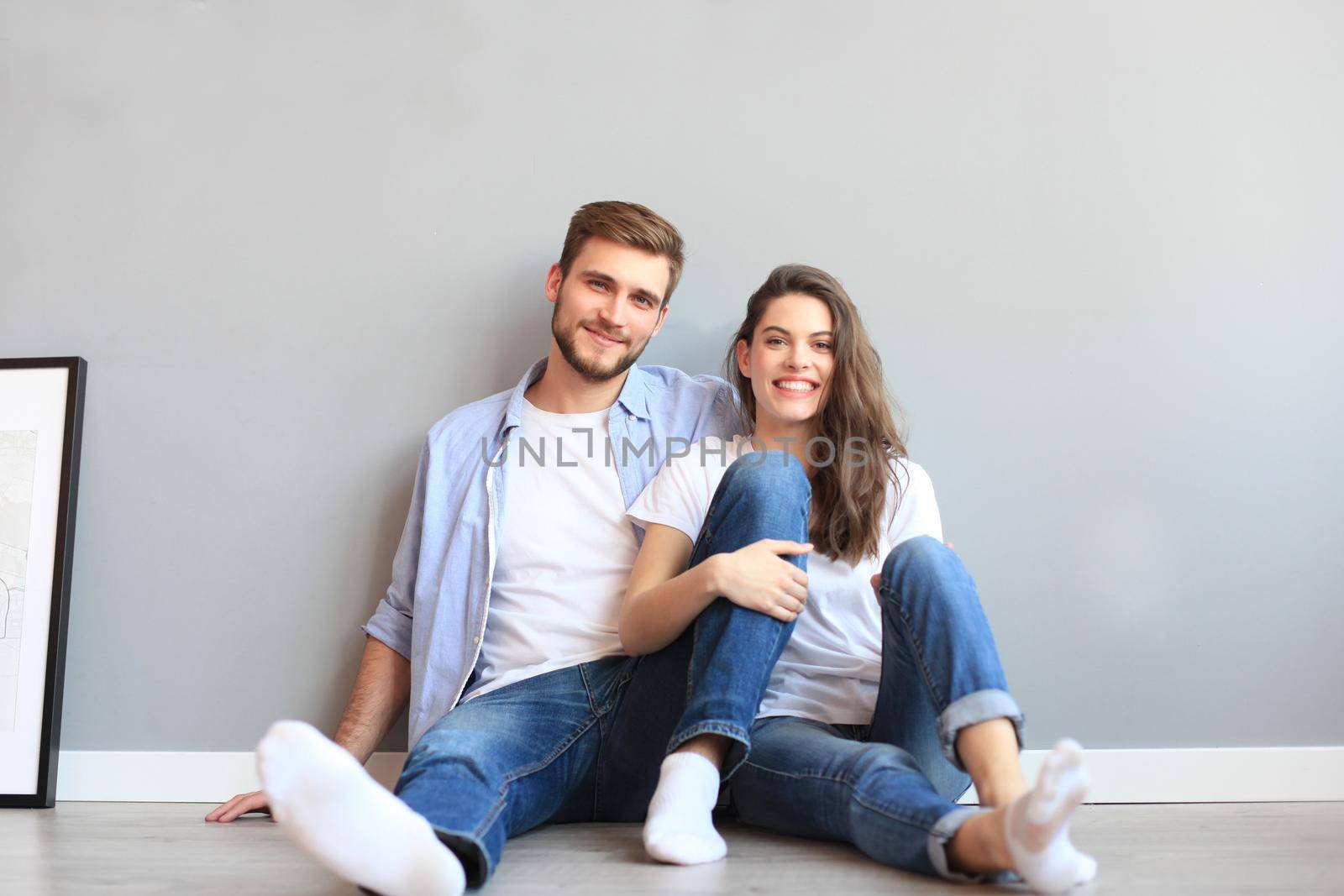 The happy couple sitting on the background of the gray wall