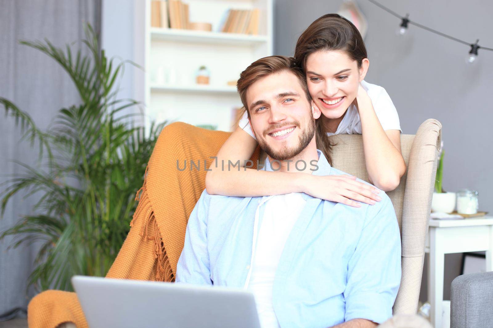 Young couple doing some online shopping at home, using a laptop on the sofa