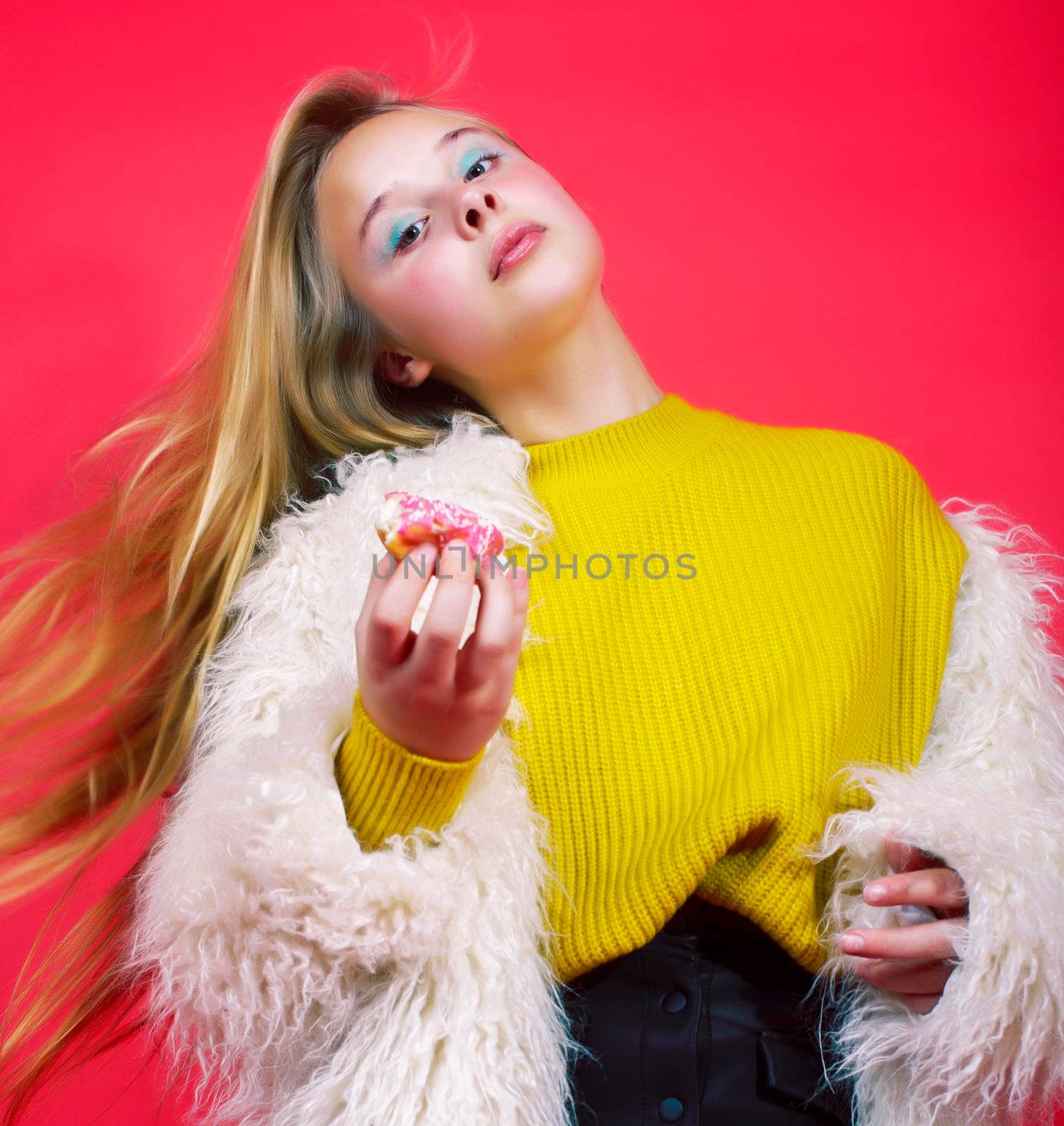 little cute blond teenage girl posing in fashion style with donut on red background, lifestyle people concept close up