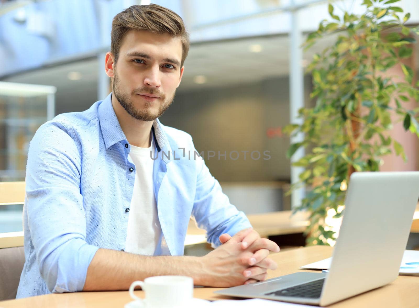 Portrait of young man sitting at his desk in the office